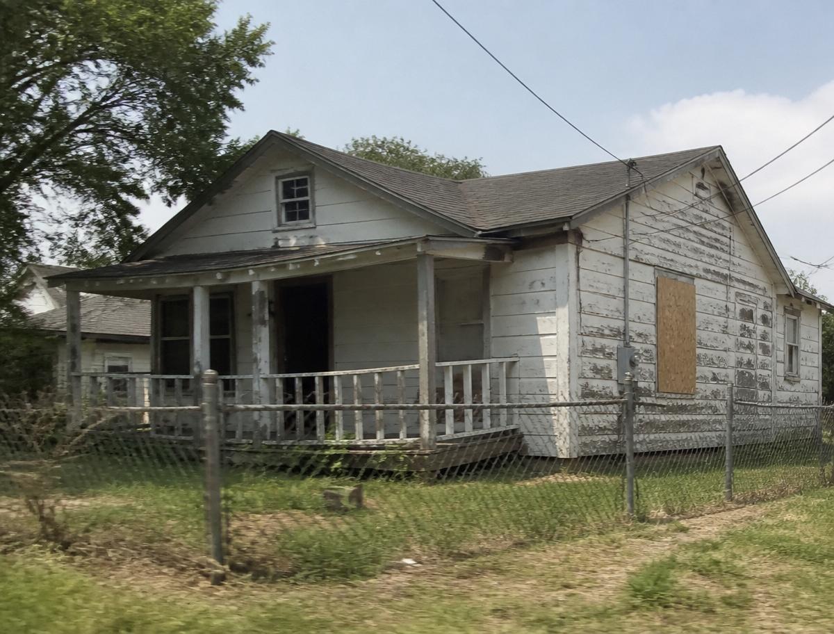 Weathered San Antonio bungalow with peeling paint and boarded window before Legacy bought it